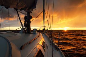 184828240 yacht blanc naviguant en pleine mer au coucher du soleil une vue du pont sur la proue le mat les e1703349046739